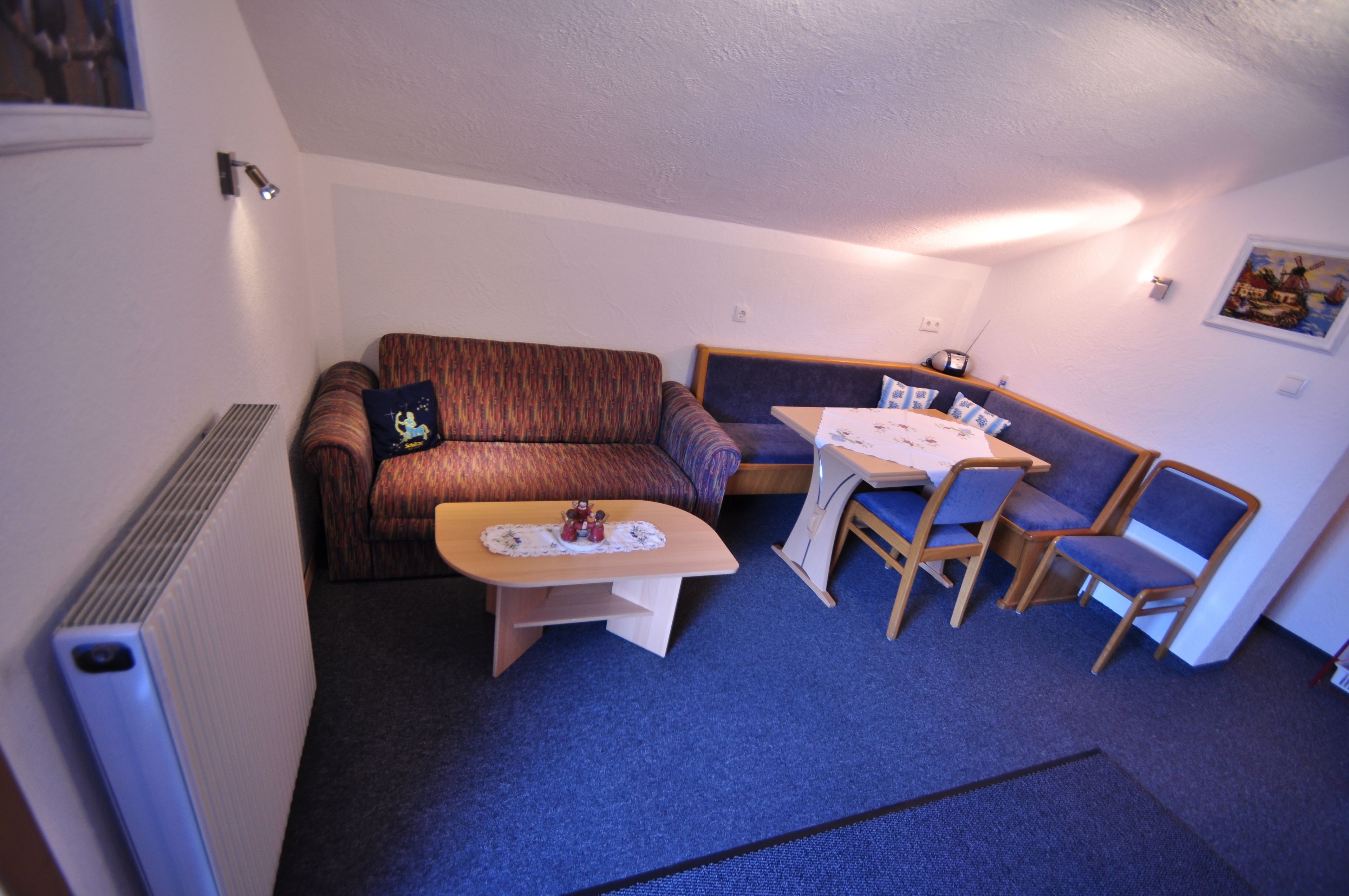 Une pièce de taille modeste, comprenant un canapé, une petite table et deux chaises.