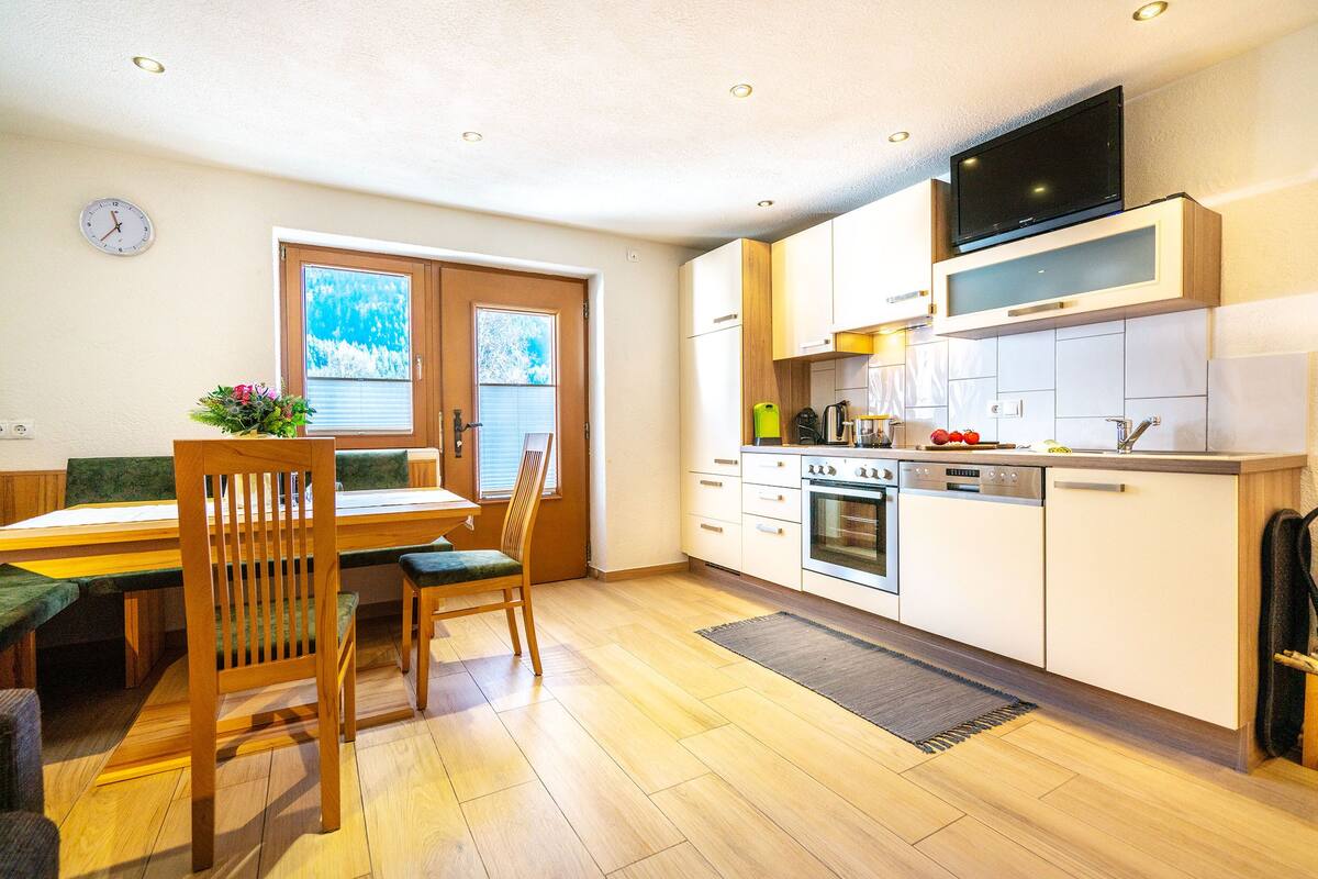 A modern kitchen with wooden cabinets, a built-in oven, and a television above the counter.