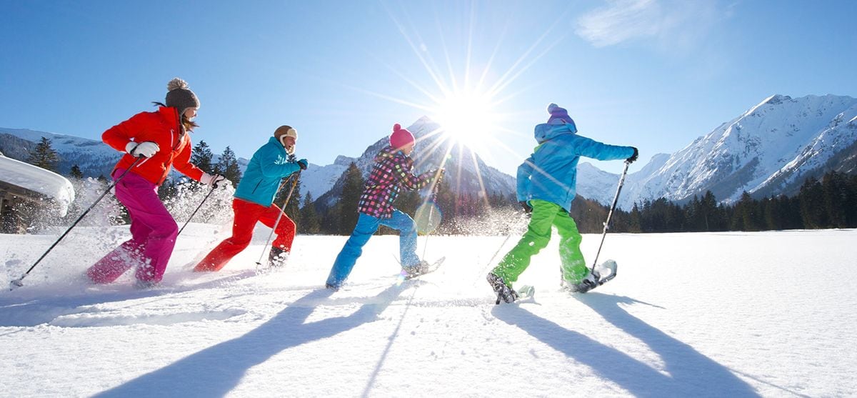 Four skiers skiing on a snowy slope with mountains in the background.