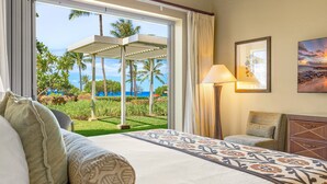 Ein Hotelzimmer mit Bett, Stuhl, Lampe und Blick auf das Meer und Palmen.