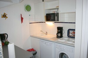 Een koelkast, een vaatwasser, kookgerei, borden en bestek