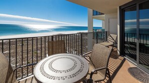 Un balcon avec une table et des chaises donnant sur une plage.