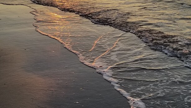 A beach at sunset with waves gently lapping onto the shore. - Welcome to "Ocean Sunrise". Renovated direct ocean front private end unit.  (Wildwood Crest)
