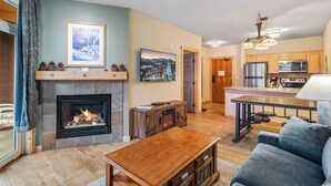 A living room with a fireplace, a sofa, a coffee table, and a kitchen area with a refrigerator and microwave. - Ski In-Ski Out Exclusive Lift Access Resort Condo at Mammoth Mountain Lakes CA (Mammoth Lakes)