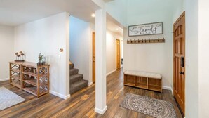 A spacious hallway with a wooden bench, a staircase, and a wall-mounted sign.
