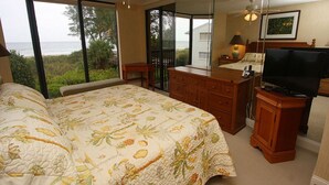 Un dormitorio con una cama grande, un escritorio, un televisor y vistas al océano.