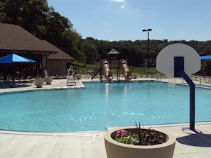 Relax by the pool surrounded by lounge chairs and umbrellas, with a basketball hoop nearby for recreation.