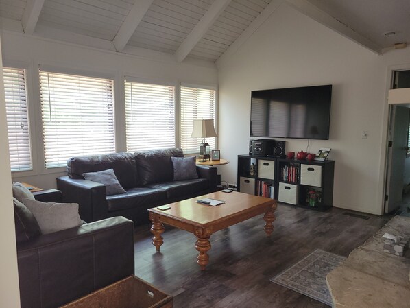 Ein Wohnzimmer mit einer Couch, einem Couchtisch, einem Fernseher und Bücherregalen.
