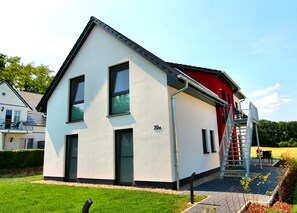 A modern two-story house with a red front door and a visible staircase leading to the upper floor.