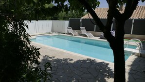 A swimming pool with lounge chairs, a stone patio, and a white fence. - In the heart of the Luberon Luxury apartment with private heated pool in a quiet  (Reillanne)