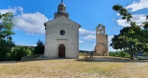 Un edificio storico con un campanile e una struttura centrale, circondato da alberi e un cielo sereno.