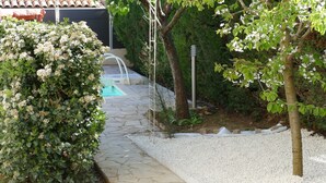 A garden with a stone pathway leading to a pool, surrounded by greenery and a white gravel area. - In the heart of the Luberon Luxury apartment with private heated pool in a quiet  (Reillanne)