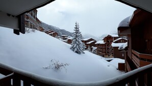 Un poble de muntanya nevat amb edificis de fusta i un arbre cobert de neu.