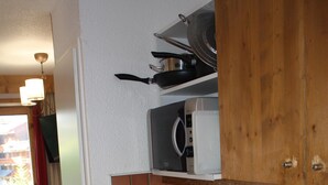 Cuina compacta amb rentaplats, microones i cafetera a la barra.