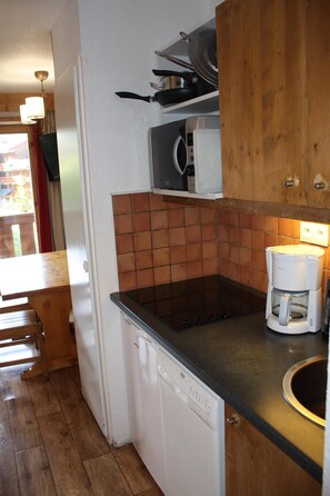 Een kleine keuken met een vaatwasser, een magnetron en een koffiezetapparaat op het aanrecht.