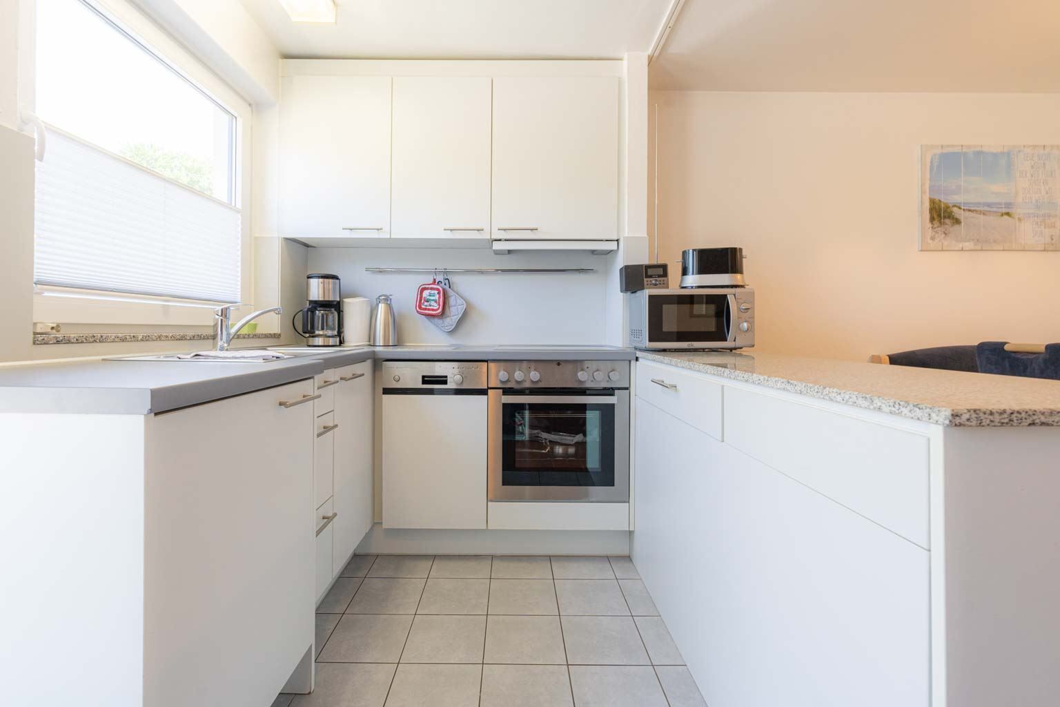 A compact kitchen with white cabinets, a built-in oven, a microwave, and a coffee maker.