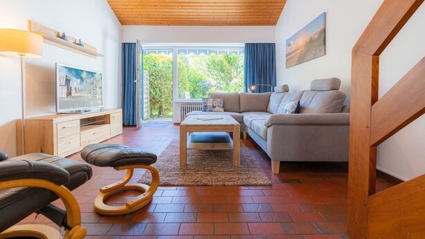 A modern living room with a wooden ceiling, a sofa, a coffee table, and a TV on a wooden stand.