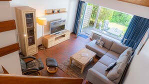 A modern living room with a sofa, coffee table, TV, and a wooden cabinet.