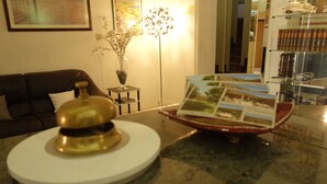 A room with a round table, a small vase with flowers, a framed picture on the wall, and a glass display case with items. - Hotel le Préjoly (Saint-Vallier-de-Thiey)