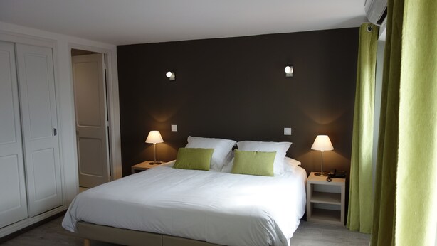 A bedroom with a large bed, two bedside tables with lamps, a wardrobe, and a green curtain. - Hotel le Préjoly (Saint-Vallier-de-Thiey)
