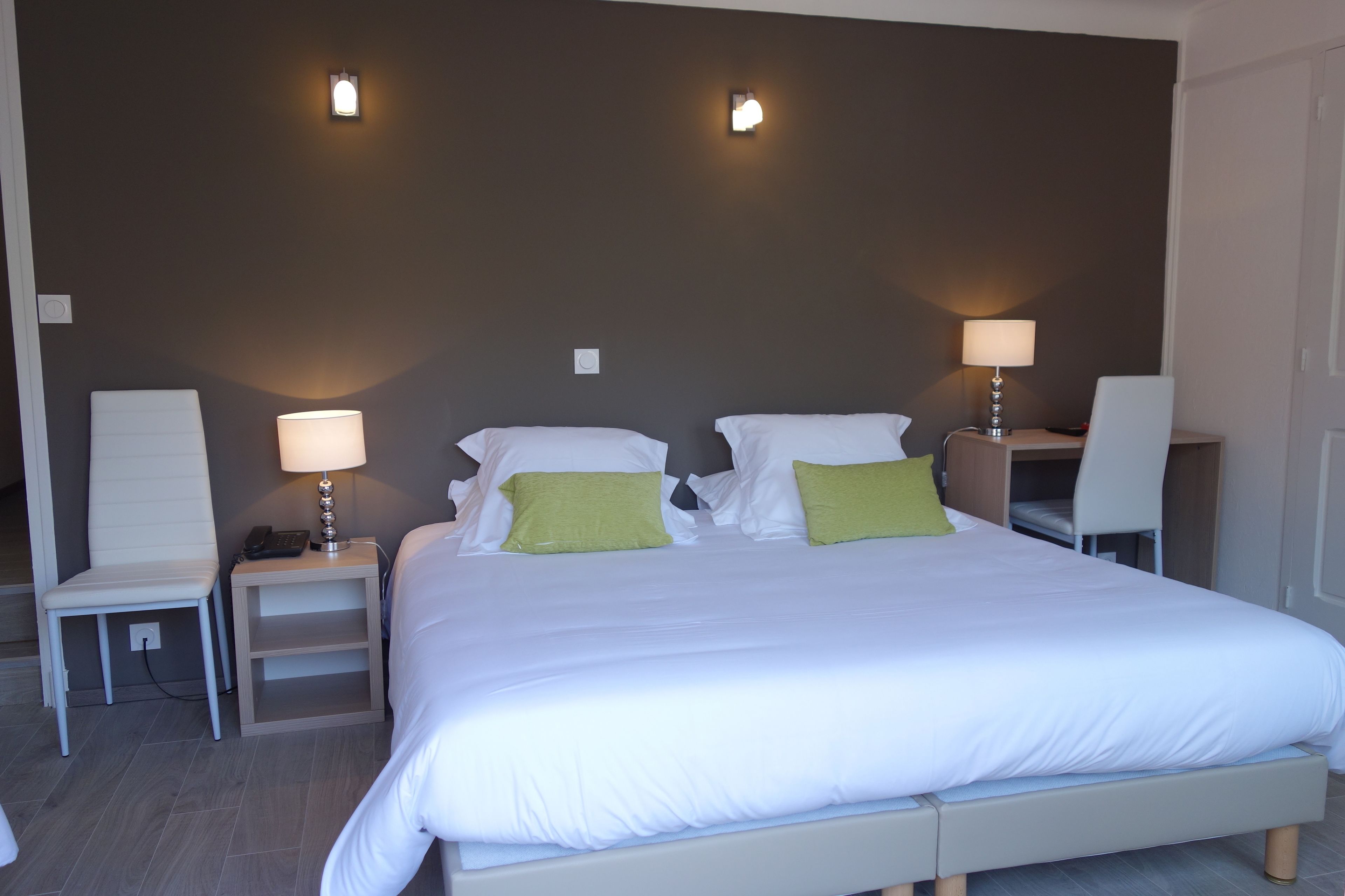 Una habitación de hotel con una cama grande, dos mesitas de noche con lámparas, una silla y un escritorio con una silla.