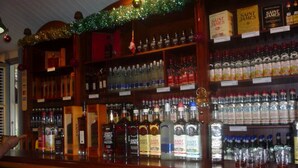 Un bar con estantes llenos de botellas de licores varios, incluyendo marcas como Saint James.