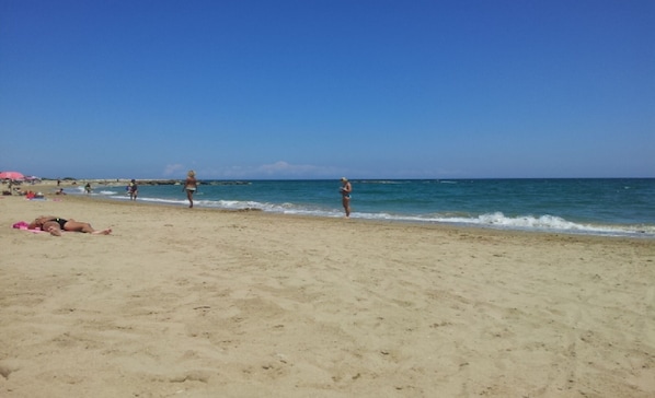 A beach with people sunbathing and walking along the shore.