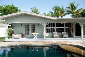 A house with a covered patio, a pool, and palm trees in the background. - BEACH NEST IS GETTING A RENOVATION! WE WILL BE BACK! CHECK BACK FOR UPDATES! XOX (Anna Maria)