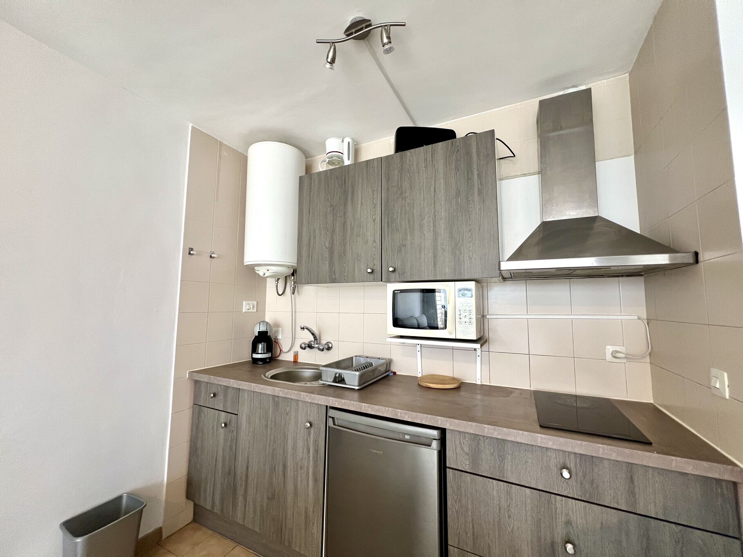 A compact kitchen with a built-in microwave, a coffee maker, and a dishwasher.