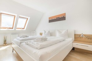 Une chambre à coucher moderne avec un grand lit, une table de chevet en bois et un tableau représentant un paysage urbain accroché au mur.