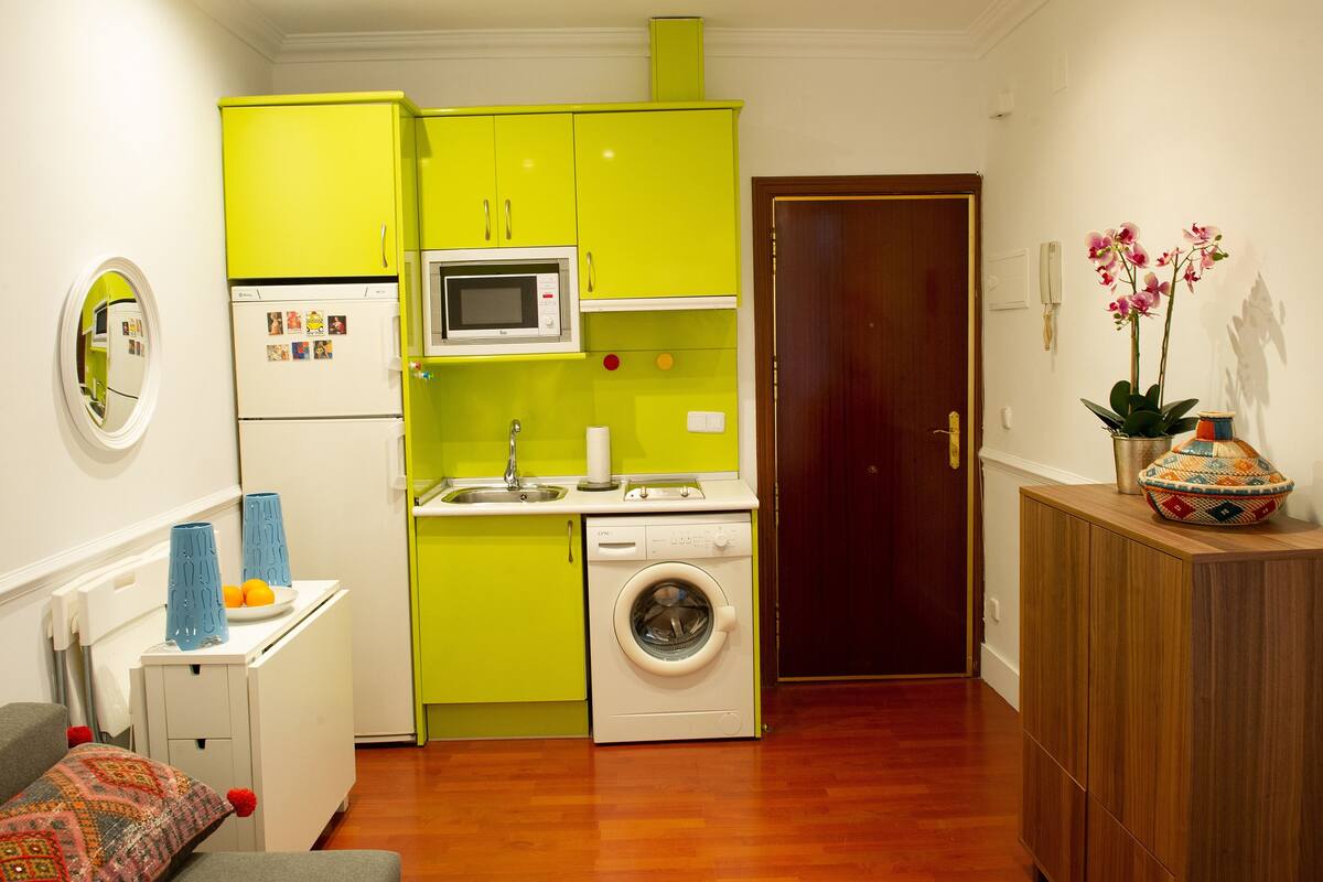A compact kitchen with a washing machine, a microwave, and a sink.