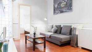 A modern living room with a grey sofa, a wooden coffee table, and a cityscape painting on the wall. - Glorieta de Bilbao Madrid Centro (Madrid)