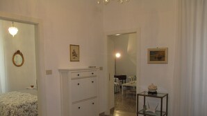 A bedroom with a bed, a dresser, a mirror, and a door leading to a dining area.