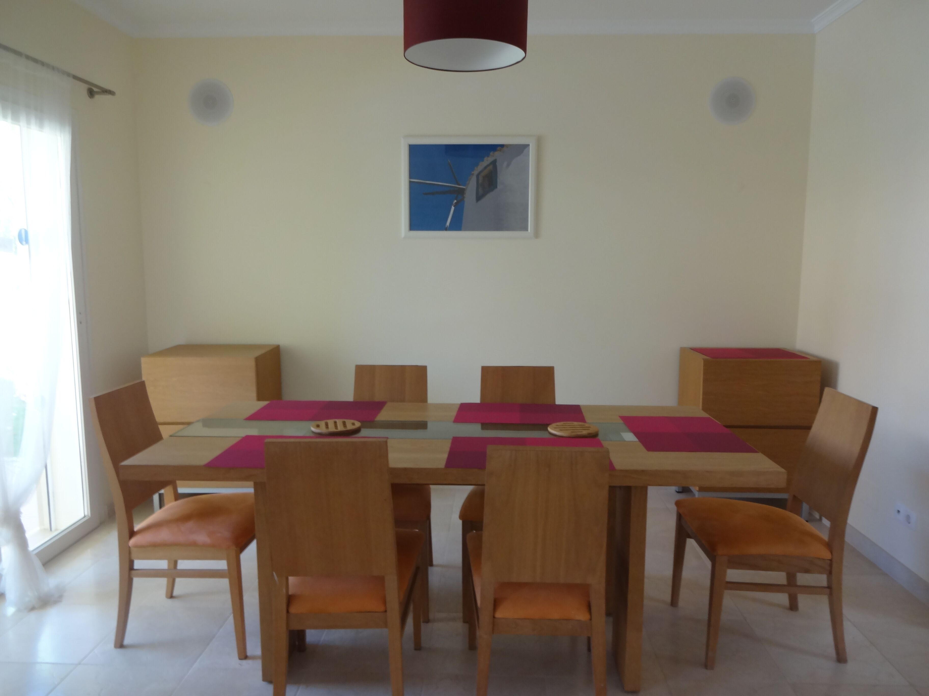 A dining area with a rectangular table, six wooden chairs, and a ceiling light fixture.