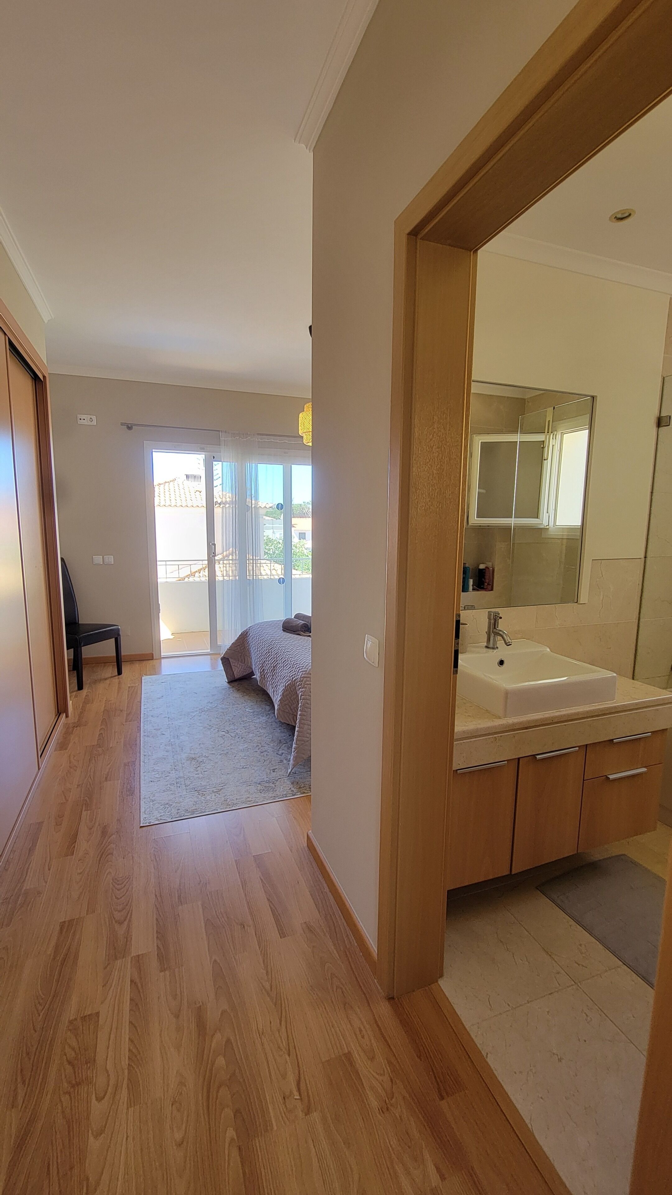 An open-plan living area with a wooden floor, a large window, and a balcony.