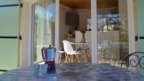 A covered patio area with a table set for two, a coffee pot, and a vase with flowers. - Sunny holiday in the quiet countryside with pool. (Lalbenque)