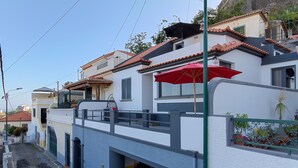 Un edificio residencial con balcón, una sombrilla roja y una escalera que lleva a un nivel superior.