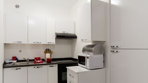 Una cocina moderna con armarios blancos, un lavamanos de acero inoxidable, un microondas y un horno empotrado.