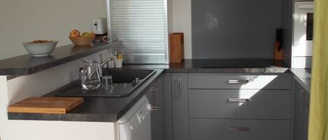 A compact kitchen with a sink, a toaster, and a bowl of fruit on the counter.