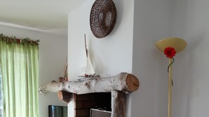 Un salón con chimenea, televisor, sofá, una mesa con un florero y una lámpara.