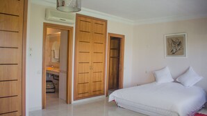 Un dormitorio con cama, armario de madera y baño a la vista a través de una puerta abierta.