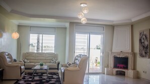 Amplia sala de estar con un conjunto de sofá color beige, una mesa de centro y una chimenea.