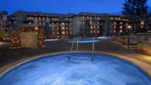 Un hôtel doté d’une grande piscine extérieure, de statues d’ours en pierre et de nombreuses fenêtres illuminées.