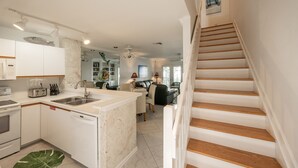 Een moderne keuken met witte kasten, een centraal eiland en een zithoek met een bank en tafel.