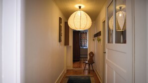 A hallway with a wooden floor, a rug, a chair, and a hanging light fixture. - A cozy and quiet vacation rental with a paved, flower-filled courtyard, just 5 minutes from downtown (Ribeauvillé)