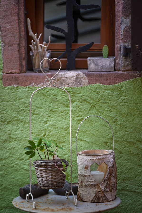 Un décor extérieur rustique agrémenté d’un mur végétal, d’une fenêtre à cadre en bois et d’une petite étagère ornée d’objets décoratifs.