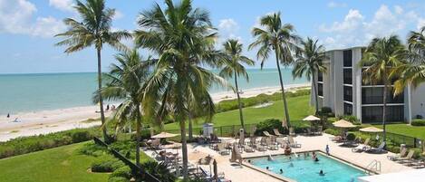 A resort with a swimming pool, palm trees, and a beach view.