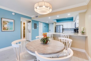 A modern kitchen with white cabinets, a stainless steel refrigerator, and a countertop with a coffee machine.