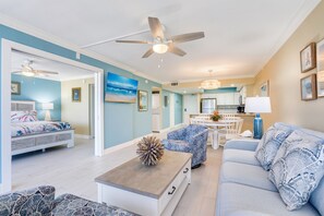 A spacious living area with a ceiling fan, a dining table, and a kitchen in the background.