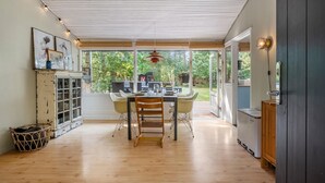 Una cocina moderna con una mesa y sillas de madera, un armario empotrado y vistas al jardín a través de amplios ventanales.